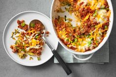 a casserole dish with meat, cheese and vegetables on the side next to a spoon