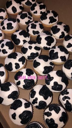 cupcakes with black and white frosting are in a box on the table