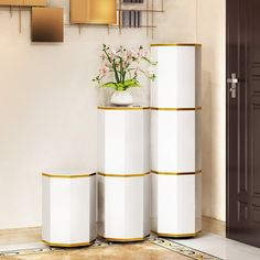 three white vases with flowers in them sitting on a floor next to a wall