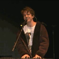 a man standing at a keyboard in front of a microphone