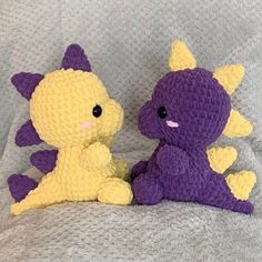 two crocheted stuffed animals sitting next to each other on a gray blanket together