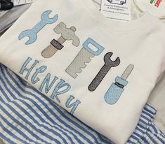 a white shirt with tools on it sitting next to some scissors and other items in front of them