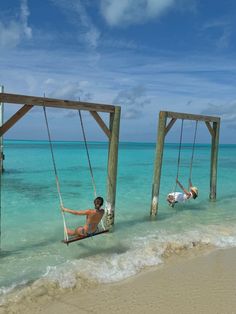 two people laying on swings in the ocean