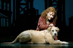 a woman sitting on the ground with a dog in front of her and looking down