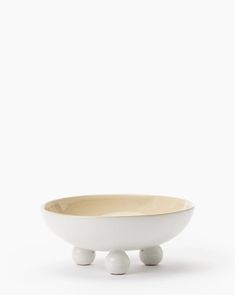 a white bowl sitting on top of a wooden stand with two balls in the middle