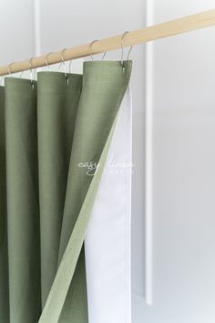 green curtains hanging on a wooden rod in front of a white wall