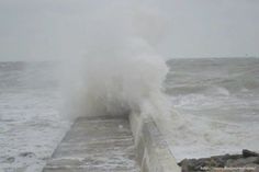 a large wave crashing over the side of a pier