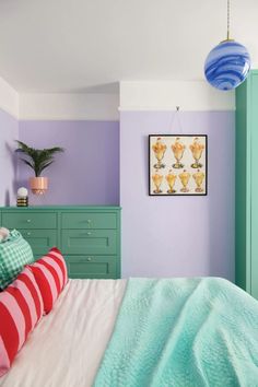 a bedroom with green and purple walls, striped bedding, and a painting on the wall