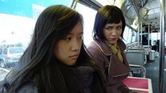 two women sitting on a bus looking at their phones