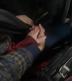 two people holding hands while sitting in the back seat of a car with their luggage