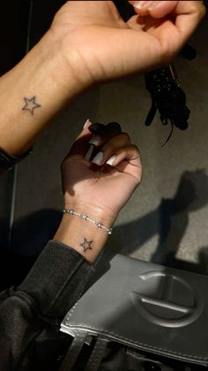 a woman's hand with a star tattoo on her left wrist, holding onto a cell phone