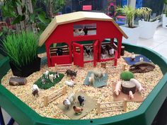 there are many farm animals in the small toy house with gravel and rocks around it