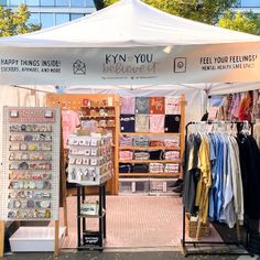 a white tent with clothes on display in front of it and the words kyn you behind it