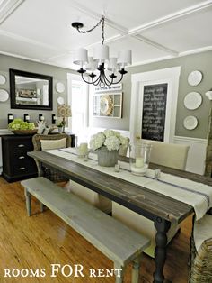 the dining room table is set with white flowers in vases and plates on the wall