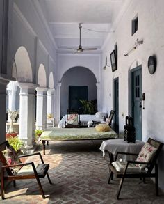 an outdoor patio with chairs and tables on the side, surrounded by arches and columns