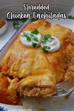 Two enchiladas sitting on a plate topped with melted cheese, sour cream, and cilantro. Shredded Chicken Rice, Chicken Rice Beans, Cilantro Lime Salsa, Dinner Hacks, Shredded Chicken Enchiladas, Chicken Enchilada Casserole Recipe, Make Shredded Chicken, Enchilada Casserole Recipes, Side Salad Recipes