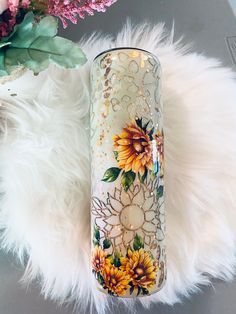 a white vase with sunflowers painted on it next to some pink and green flowers