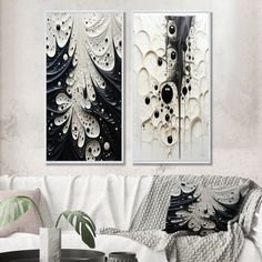 two black and white paintings hanging on the wall in a living room next to a couch