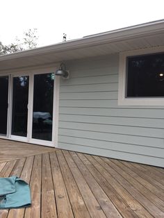 an empty blue towel sitting on top of a wooden deck next to a building with windows