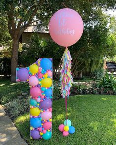 a birthday cake with balloons and streamers on the lawn in front of a house