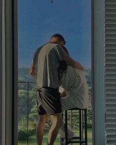 two people standing on a balcony looking out the window