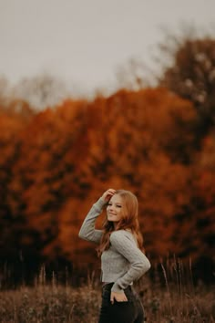 a woman standing in the middle of a field with her hands on her head and looking into the distance