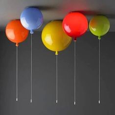 colorful balloons are hanging from the ceiling in a room with gray walls and flooring