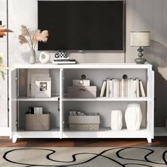 a white entertainment center with books, vases and a television on it's stand