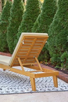 a wooden lounge chair sitting on top of a rug