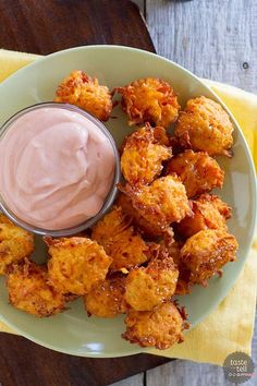 a white plate topped with tater tots next to a bowl of dip