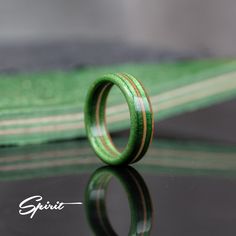 a wooden ring sitting on top of a black table next to a green cloth with the word spirit written across it