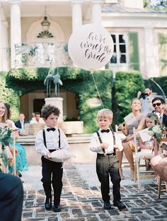 two young boys in tuxedos are walking down the aisle at a wedding ceremony