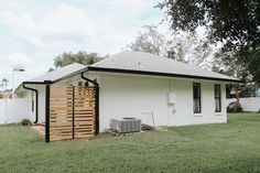 a small white house sitting on top of a lush green field next to a tree