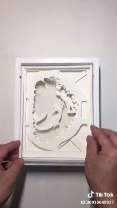 two hands are holding up a paper cutout