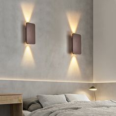 a bed sitting under two wall lights in a bedroom