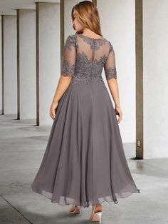 a woman in a gray dress with sheer sleeves and lace on the top is looking back