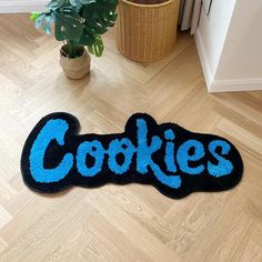 a blue rug with the word cookies on it in front of a potted plant