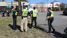 three police officers are talking to each other on the side of the road in front of a truck