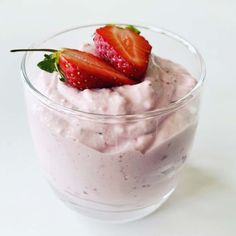 two strawberries on top of a bowl of yogurt