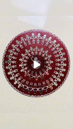 a red and white plate with an intricate design on the top, sitting on a table