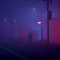 a man standing in the middle of a foggy street with traffic lights above him