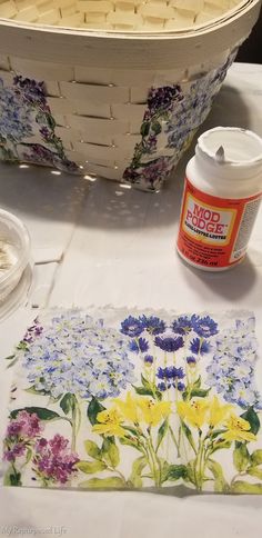 the table is covered with flowers and other crafting supplies, including a basket full of paint