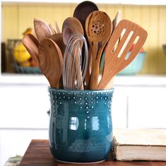 wooden utensils and spoons in a teal cup on a kitchen counter