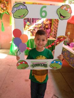 a young boy holding up a sign with the number six on it