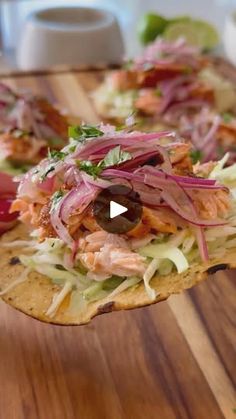 a wooden table topped with two tacos covered in toppings