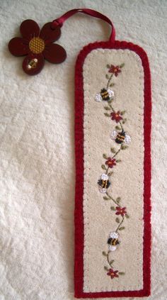 a red and white bookmark with flowers on it next to a flower brooch