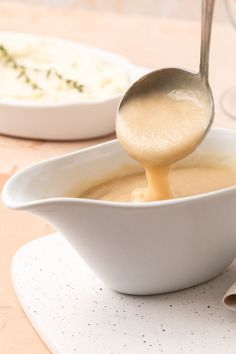 a spoon is pouring gravy into a bowl