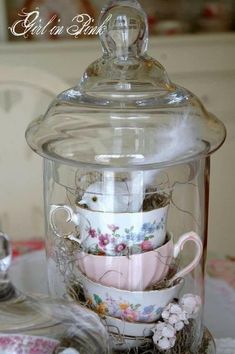 a glass jar filled with tea cups and saucers