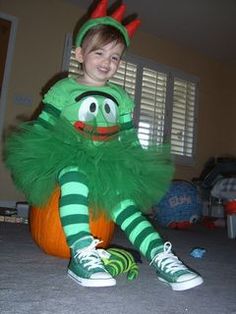 a young boy dressed as a green monster sitting on the floor