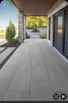 an outdoor patio with stone walls and plants on either side, surrounded by graveled walkways